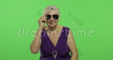 一位戴太阳镜的老妇人笑了。 老奶奶。 铬键